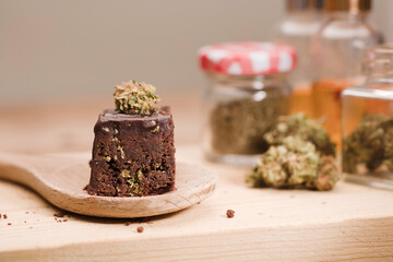 Chocolate cupcake muffins with cannabis buds on wooden spoon. Marijuana hemp in food dessert. Chocolate herb muffins cooking. Marijuana cake on a brown wooden table.
