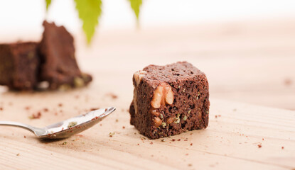 Chocolate cupcake muffins with cannabis buds. Marijuana hemp in food dessert. Chocolate herb muffins cooking. Marijuana cake on a brown wooden table. green marijuana leaf in the background