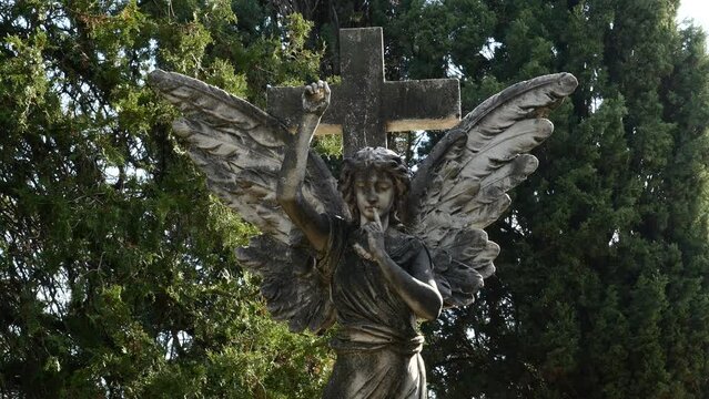 Detalle de una estatua de un &aacute;ngel con una cruz.