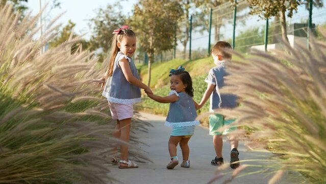 Ni&ntilde;os Felices amigos hermanos amistad caminando juntos tomados de la mano disfrutando y divertidos jugando en el parque