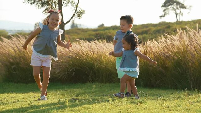 Ni&ntilde;os Felices hermanos amigos combinados vestidos igual jugando bailando riendo alegres disfrutando divertidos en el parque en el jard&iacute;n al aire libre al exterior