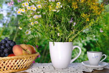 cup of tea, beautiful summer bouquet of wildflowers, handmade lace white doily on the table, summer time concept, tea drinking in the garden