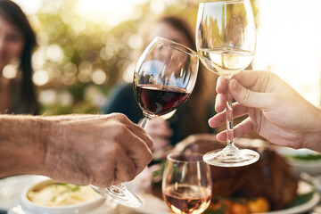 Heres to all of us being here today. Shot of a group of cheerful people celebrating with a toast over a dinner table outside.