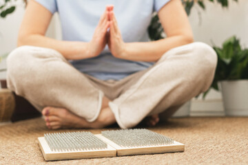 Woman of European appearance sits in lotus position with wooden sadhu board nails for sadhu practice.