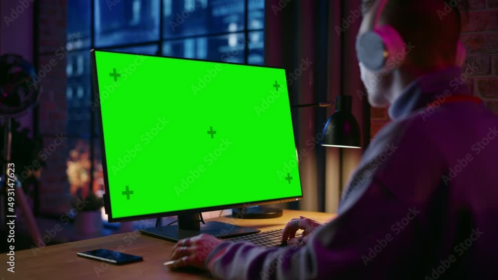 Aufkleber young handsome man in headphones working from home on desktop computer with green screen mock up dis