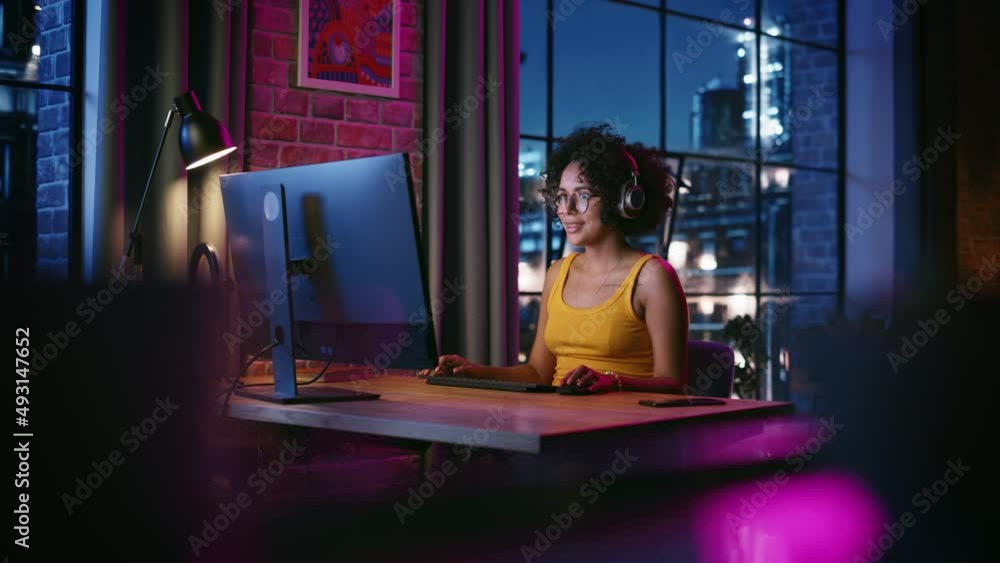 Poster young multiethnic woman in chatting on video call on computer in stylish loft apartment in the eveni