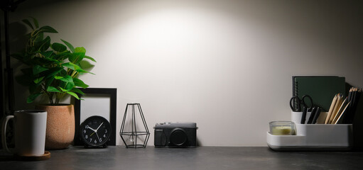Stylish workplace with stationery, picture frame and potted plant on black table. Copy space for graphic display montage.
