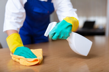 Closeup shot of hands of professional cleaning service worker in rubber gloves wiping wooden table...