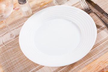 Table setting for dinner, empty plate, fork and knife on napkin - dishware top view