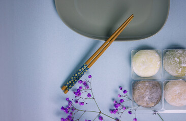 Traditional Japanese dessert mochi in rice dough. Gray plate, chopsticks on blue