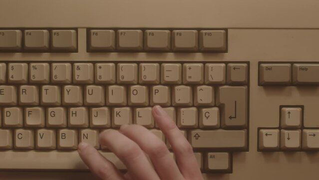 Hands typing on the keyboard of an old micro computer. Aerial view.