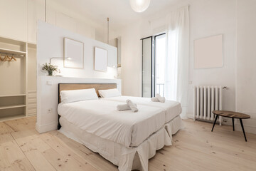 Bedroom with double beds joined together, white bedding, rolled towels on the beds, and white decor...