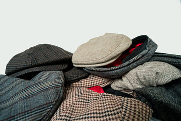 Stacks of classic hats like newsboy hats and flat hats in different colors and designs on a white background