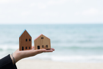 Obraz na płótnie Canvas small home model on hand with sea background, miniature house