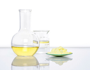 Closeup chemical ingredient on white laboratory table. Sulfur Powder in Chemical Watch Glass place next to Aluminium chloride liquid, oil and alcohol in Beaker. Side View