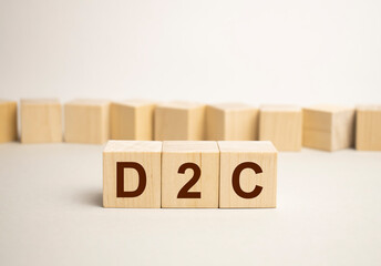three stone cubes on the background of white financial statements, tables with the word D2C - acronim Direct to Consumer. Strong business concept. Gray background.