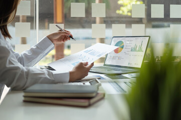 Close up hands of business asian woman working in the office with documents That represents the investment results of the company Profits between companies that have made a mutual agreement.