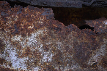 Rusty metal wall, old iron sheet covered with rust. The rusty iron sheet is covered with white paint.