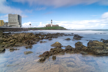 Fototapeta premium The historic architecture of Salvador in Bahia, Brazil showcasing the Farol da Barra Lighthouse at Bahia de Todos os Santos Bay on a sunny summer day