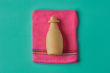 Bottle of artisanal Mexican mezcal and tequila with a palm cover. On colorful background. Mexican pink and water green.