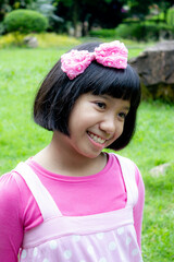Portrait of a happy Asian girl with big pink bow and short black hair, smilling