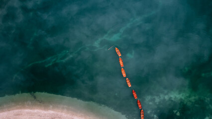 Aerial drone view of wooden boats on water surface with blue sky reflection in lake. Braies Lake, Italy