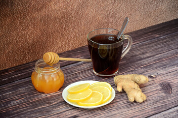 Alternative medicine, folk remedy for colds, hot tea, honey, lemon and ginger root on a wooden table.