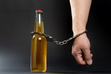bottle of beer and a hand locked by handcuffs