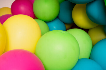 Colorful balloons all over the frame, lying one next to the other.  Many colored balloons looking like colored balls