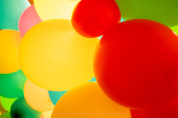 Colorful balloons all over the frame, lying one next to the other.  Many colored balloons looking like colored balls
