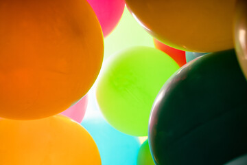 Colorful balloons all over the frame, lying one next to the other.  Many colored balloons looking like colored balls