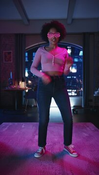 Vertical Screen: Diverse Multiethnic Young Black Female Dancing in Futuristic Neon Glowing Glasses, Having a Party at Home in Loft Apartment. Recording Funny Viral Videos for Social Media.