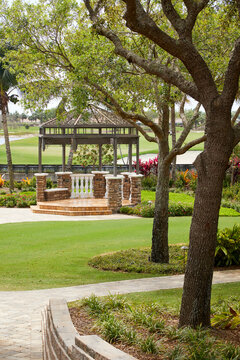 Outdoor gazebo with flowers, green grass and trees in a vertical format image