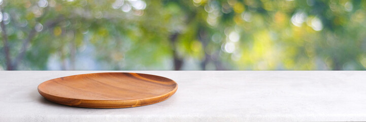 Empty wooden plate on white table over blur green trees nature with bokeh background, Blank wood dish for food display montage banner template, muck up, poster, wallpaper