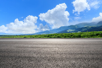 Empty asphalt road and green mountain nature scenery under blue sky. Road and mountains background.