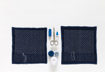 Needlework. Process of hand embroidering with white threads on blue fabric in the style of...