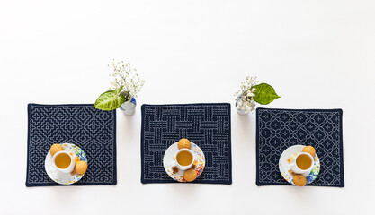 Afternoon tea table setting with homemade biscuits and green tea cups on blue napkins hand...