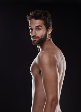 Im a lover not a fighter. Portrait of a handsome man standing shirtless against a black background.