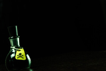 vial of poison with a hazard warning label, on a dark background, toning, short focus