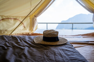 Hat is placed on the bed inside the tent, in front of the mountain view.
