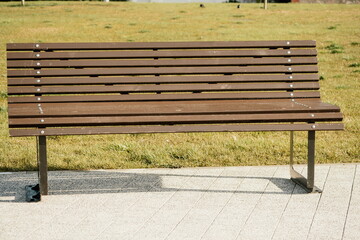 Sea side public park with wooden bench in spring evening. No people.