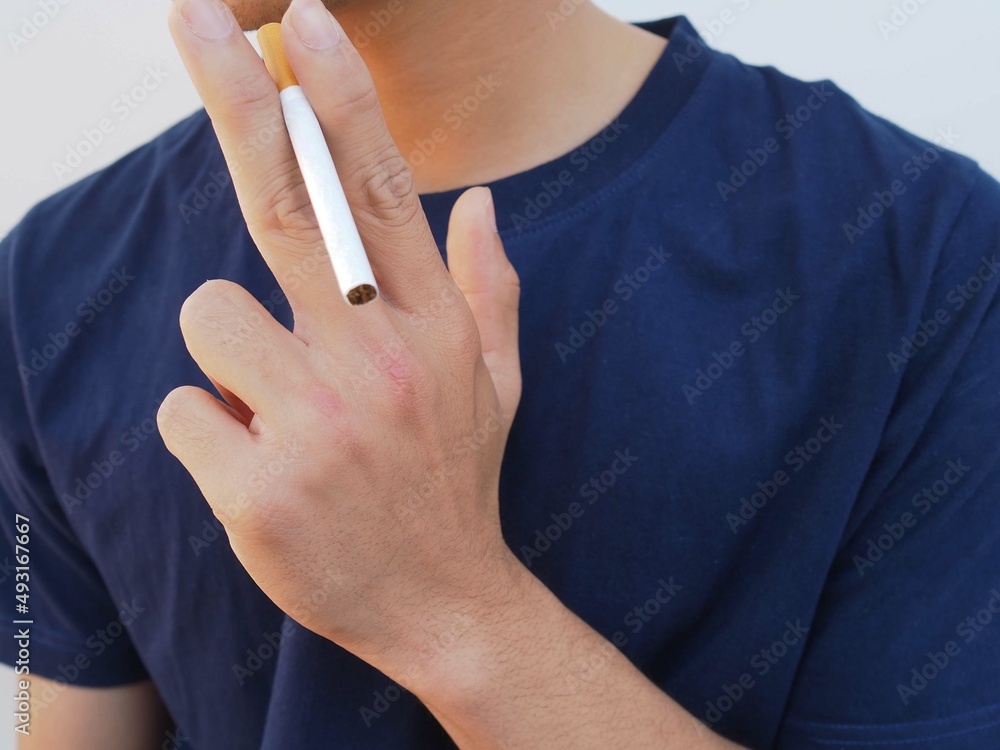 Wall mural young man smoking a cigarette on white background.