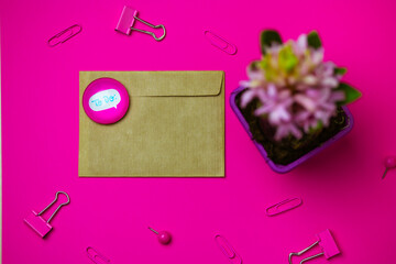 Brown envelope on pink background view from above. Stationery - pink paper binders, paper clips. Potted spring hyacinth flower in bloom on table Female desk with a letter, magnet stack with text TO Do