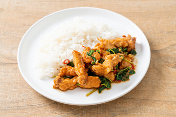 stir-fried fried fish with basil and chili in thai style topped on rice