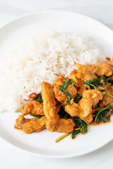 stir-fried fried fish with basil and chili in thai style topped on rice