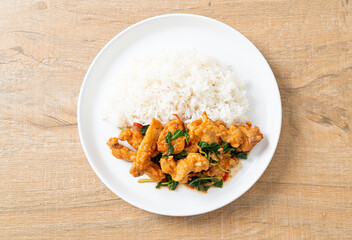 stir-fried fried fish with basil and chili in thai style topped on rice