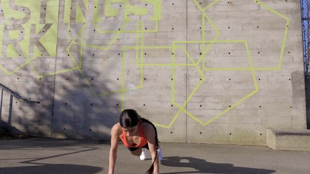 Young Woman Doing Burpee Exercises Routine While Working Out Outside