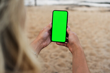 Girl on the beach holding a smartphone with Green screen. Chroma Key - Powered by Adobe