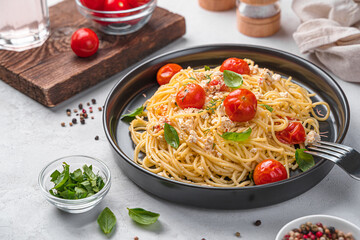Fetapasta, spaghetti with feta cheese, cherry tomatoes and herbs on a gray background.