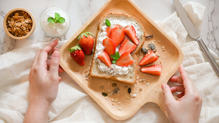 Female hand serving a plate of healthy yummy strawberry toast